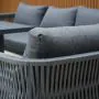 Aurora lounge garden furniture set featuring a modern grey rope design with comfortable cushions and fire pit table. Elegantly arranged in a garden setting with sleek cladding in the background