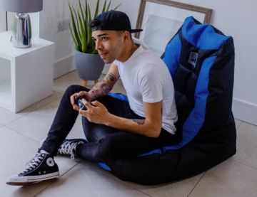 Man Plays Video Games on the PlayStation Official Bean Bag Chair in the Living Room 