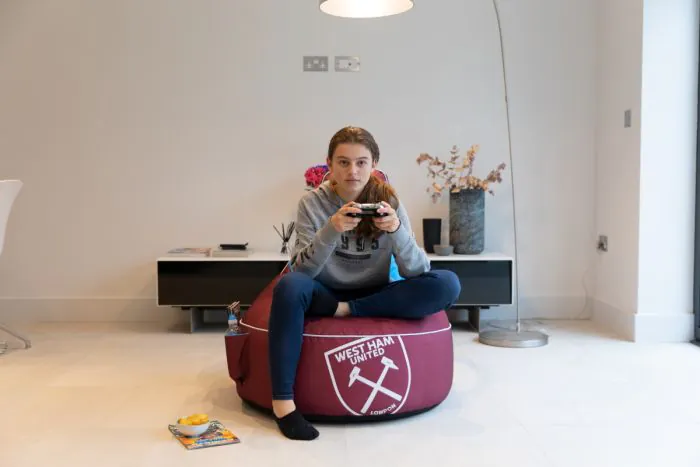 Front View of the Girl Sitting on the West Ham United F.C. Gaming Bean bag Chair in the Living Room 
