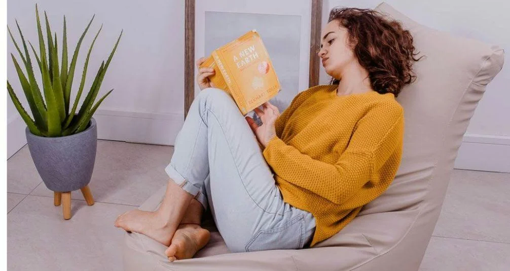 Woman sitting reading on high back bean bag
